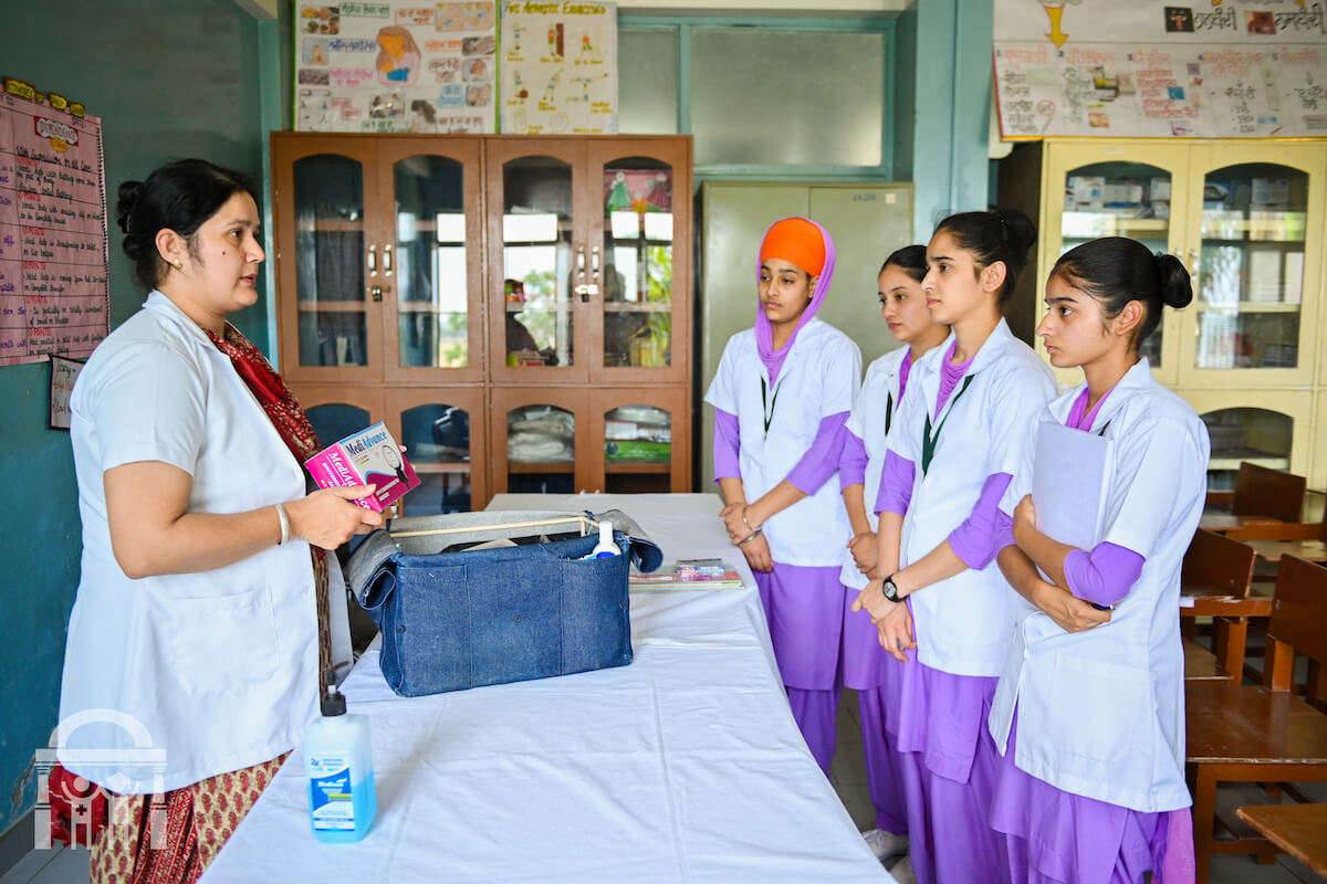 Guru Nanak College of Nursing community lab session showing nurse travel kit with teacher and students in Dhahan Kaleran