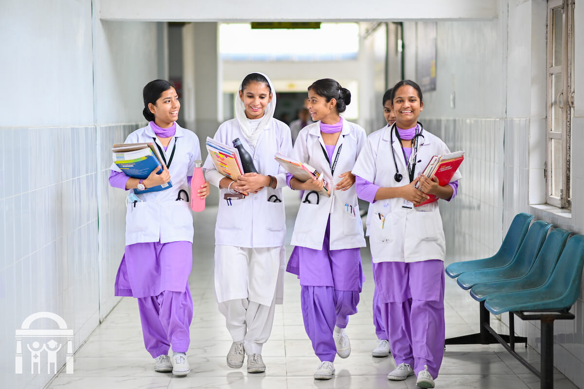 Guru Nanak College of Nursing students with books walking down hallway for clinical practice